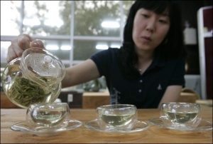 Владелица чайного дома в южнокорейском регионе Босонг готовит для посетителей зеленый чай. К нему подает печенье из чайных листьев