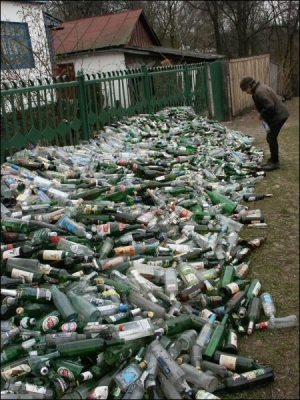 Галина Рябець перебирає пляшки біля свого будинку