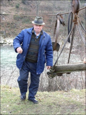 68-летний Михаил Росоха показывает подвесное корыто, с помощью которого переправляется через реку