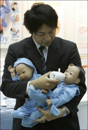 Представник компанії ”Ямазакі” на виставці роботів у Токіо демонструє, як можна годувати робота-немовля