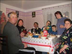 Петр Грицищук (крайний слева) в селе Малый Раковец Иршавского района Закарпатской области за праздничным столом со своей семьей. Рядом с шампанским — самогон градусов под 60