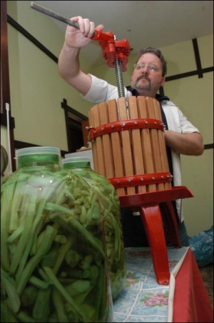 Столичный трактирщик Михаил Романов показывает, как работает дубовый итальянский пресс для ягод. Рядом — бутыли с ”хреновухой”