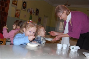 Вихователька дошкільного навчального закладу №61 Марія Прокопів годує супом-пюре Оксанку, 3 роки. 4-річну Роксоланку (ліворуч) батьки навчили їсти самостійно. З нового року 40 дітей можуть опинитися на вулиці. Власником львівського дитсадка став банк ”Киї