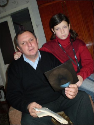 Полтавець Сергій Сисоєв із донькою Ольгою гортають медичну картку дівчинки. Після виписки з лікарні вчителі та родина однокласника, який травмував школярку, жодного разу не поцікавилися станом її здоров’я