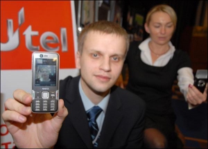 Демид Дробот із компанії ”Утел” показує свій мобільний телефон під час відеодзвінка. На дисплеї видно його колегу-співрозмовницю Маріанну Литвиненко, яка сидить позаду