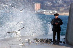 Січень 2006 року. Чоловік годує чайок та голубів і милується морським прибоєм на Артилерійській набережній у Севастополі