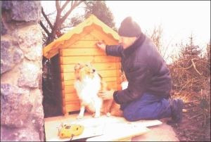 Пенсионер из села Шилы Полтавского района Дмитрий Яцко карандашом пишет на собачьей будке кличку пса. Хозяин хочет вырезать из дерева именной сруб ”Лорис”