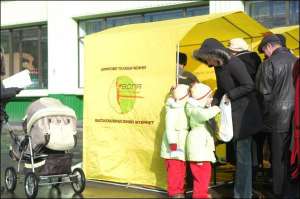 Семья киевлян с девочками-близнецами стоит в очереди в палатки компании ”Воля” на ул. Драйзера, 24 