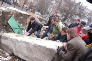 Киевляне в субботу расшатывают и толкают бетонный блок в котлован в Десятинном переулке. На акцию пришли с полсотни людей