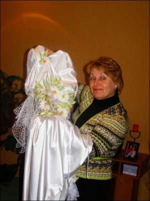 Дизайнер Татьяна Москивец из поселка Решетиловка на Полтавщине показывает платье из атласа, украшенное ажурной вышивкой ришелье. Пошила его в прошлом году на выпускной для своей внучки Марии