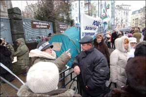 Пострадавшая от ”Элиты-Центра” голодающая киевлянка общается с прохожим возле Секретариата президента на Банковой. У протестующих сломался обогреватель, позавчера они собрали 1950 гривен пожертвований на новый