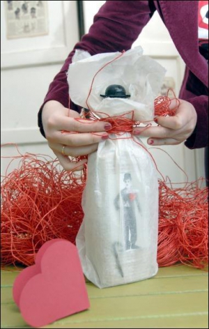 Продавець-дизайнер арт-бутику ”Азур” Олена Кулаківська запаковує пляшку в прозорий лист локти, щоб було видно зображення Чарлі Чапліна. Упаковку жінка зав’язує ниткою червоної рафії