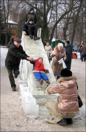 Черкасские дети катаются на ледовой горке в детском парке в центре города. Сквозь лед, из которого вылита гора, видны кусочки свежих, замороженных в ней фруктов
