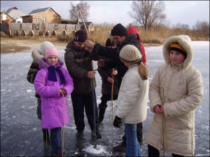 Педагог Анатолій Федоренко з Миргорода допомагає 13-річному учню Сергієві Рєзіну (в центрі) правильно визначити положення бура, щоб зробити на річці Хорол ополонку. Так вони рятують рибу від нестачі кисню