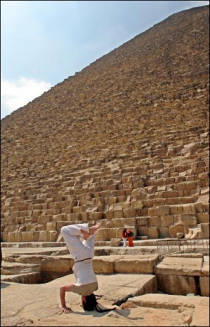 Во время солнечного затмения в конце марта 2006 года турист-европеец стоит на голове — занимается йогой — около пирамид Гизы в Египте