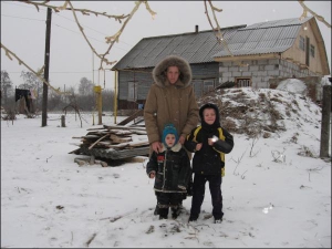 У селі Вихвостів Городнянського району Ганна Курин із синами біля хати, яку її сім’я купила на гроші сільгосппідприємства