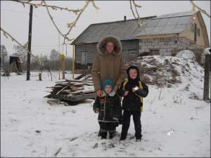 У селі Вихвостів Городнянського району Ганна Курин із синами біля хати, яку її сім’я купила на гроші сільгосппідприємства
