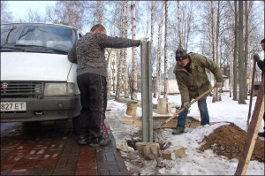 Троє робітників закопують бетонний стовпець для огорожі навколо меморіального музею ”Хата на Пріорці”. Раніше комплекс огорожі не мав