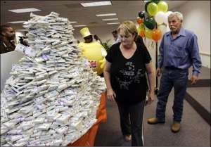 Тоня Харріс із чоловіком Робертом поряд із картонним муляжем грошей у лотерейній компанії, де їх оголосили переможцями