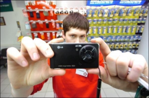 Роман Гленько зі столичного магазину ”City.com” на Петрівці показує телефон компанії LG — ”KU990 В’юті”. Мобільник має камеру на 5 мегапікселів. Новинка коштує 2749 гривень