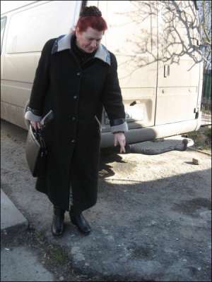 Мария Миткевич, сельский председатель Слободка-Кульчиевецкого сельсовета, стоит на своем дворе. Она показывает ямку на земле, которая образовалась от взрыва гранаты. Сзади нее — микроавтобус, который поцараполо осколками