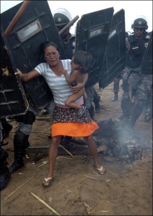 Участница ”Движения безземельных” пытается противостоять полиции, которая разгоняет крестьян с частного земельного участка