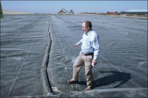 Главный технолог компании ”Био Энерджи Солюшнз” ходит по поверхности резервуара с жидким коровьим навозом. Размерами емкость равняется пяти футбольным полям