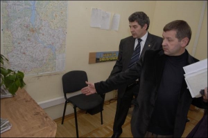 Иван Агий (спереди) и Геннадий Гера показывают место под столом в офисе партии ”Единство”, где стоял похищенный сейф. На стене сзади висит политическая реклама с выборов-2006 — \"Кияни — за Омельченко”