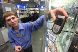 Евгений Скальский из магазина ”Юнитрейд” показывает телефон ”Самсунг Симфони”. В магазине есть мобилки красного и серого цветов