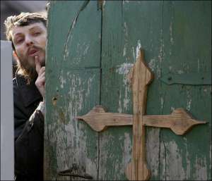 Лидер группы верующих Петр Кузнецов выглядывает из-за ворот своего дома. От конца света он не прячется в пещере вместе с последователями