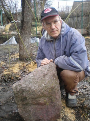 Микола Трояник тримає гранітну брилу на своєму подвір’ї. Вчений каже, що камінь має лікувальні властивості