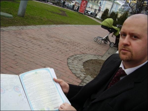 Владислав Ільченко під час зустрічі у сквері на Володимирській демонструє документи, що засвідчують його право власності на землю в Чапаївці