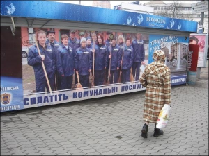 Перехожі звертають увагу на незвичний плакат на Львівській площі. Двірники та комунальники сфотографовані на ньому у повний зріст