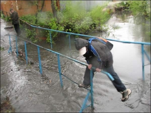 Школьник лезет через затопленный мостик по улице Талалихина в Виннице. Вода в реке поднялась на два метра из-за наваленных в нее стройматериалов. Русло расчищали спасатели