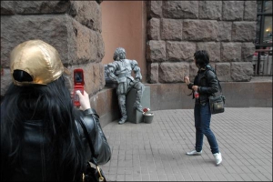 Жінки фотографують ”живий пам’ятник” біля входу в ”Пасаж” на Хрещатику. Вуличний артист признався, що кілька разів йому дуже допікали п’яні люди: вилазили на постамент, обнімалися