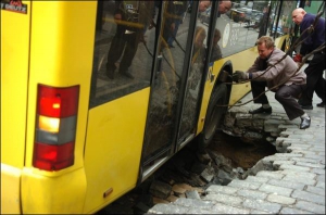 Рабочие ”Киевпасстранса” в среду на улице Грушевского крепят тросами автобус к крану, чтобы вытянуть его из намытой ямы