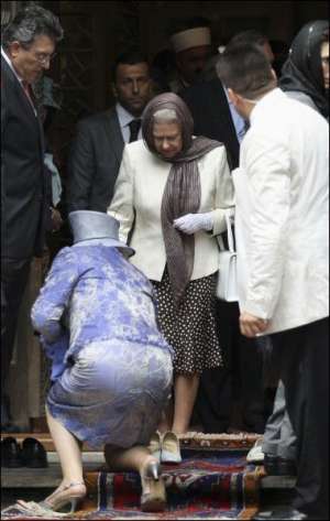Британській королеві Єлизаветі ІІ допомагають роззутися при вході до мечеті в місті Бурса
