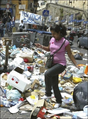Жительница Неаполя проходит мимо мусора, который в знак протеста начали выбрасывать на перекрестках улиц