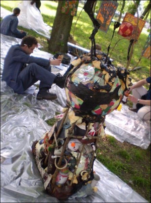 Художник Юрій Радчук сидить позаду земної кулі, яку помістив на купу сміття. Гроші від її продажу хотів віддати ВІЛ-інфікованим. Але кулю не купили