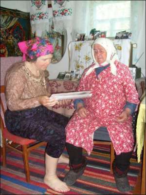 Социальный работник Анна Яременко из Малых Канивец Чорнобаивского района читает газету подопечной Анне Мелашенко. Из магазина принесла бабушке хлеб и несколько булочек