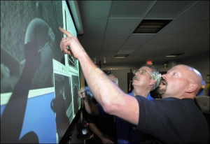 Работники американского Национального управления аэронавтики и космоса рассматривают первые снимки поверхности Марса, сделанные космическим кораблем-роботом ”Фениксом” после посадки
