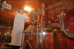 Помощник пивовара Оксана проверяет металлические резервуары для пива. Посетители ресторана-пивоварни ”Пивариум” могут наблюдать из-за столиков в зале, как варят напиток