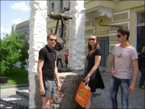 В Сумах Виталий Нестеренко, Оксана Герасименко и Вячеслав Раков разглядывают памятник сумке на улице Воскресенской. В колодец они бросили по несколько монет на счастье