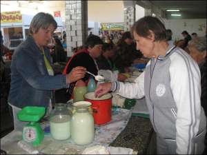 Наталия Мищенко (слева) из села Дудниково Полтавского района на Центральном рынке в Полтаве продает молокопродукты. Дает покупателю попробовать сметану