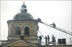Фото сделано через час после удара молнии. Купол исторической библиотеки в Лавре начал дымится во второй раз, спасатели поднимаются на него, чтобы выбросить тлеющие остатки