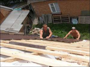 Строители 33-летний Олег Денисюк (в жилете) и 26-летний Андрей Токарчук монтируют металлочерепичную крышу на новом доме в микрорайоне Пятничане в Виннице. Под металлочерепицу мастера советуют положить пленку, чтобы крыша не протекала