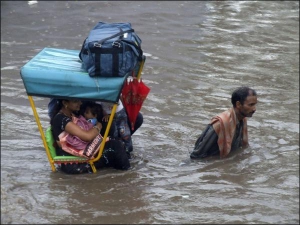 Затопленими вулицями міста Матхура рикша перевозить сім’ю, яка після дощів залишилася без оселі