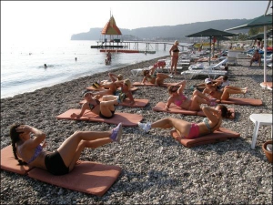 Утром на морском побережье города Кемер в Турции отдыхающие делают упражнения на укрепление пресса. Потом они будут заниматься аквааэробикой
