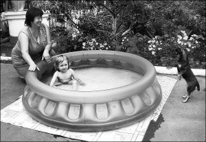 Татьяна Казмирук купает 2-летнюю внучку Софийку в надувном бассейне. Женщина купила его в Берлине, столице Германии, девочке в подарок 