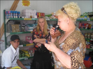 Пенсионерка Татьяна Кривонис выбирает себе парфюмерию в магазине ”Все по 5 гривен” на рынке ”Левада” в Полтаве. Женщина уже покупала в нем картину, ожерелье, парфюмерию. Ее обслуживает продавец магазина Александра Лысенко с мужем Сергеем